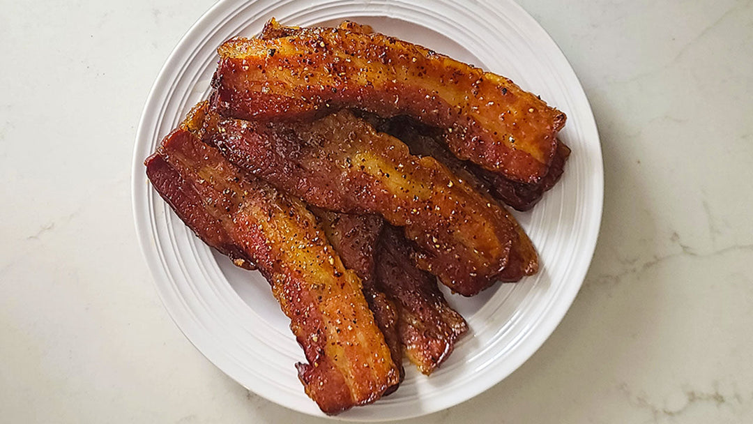 Thick slices of maple candied bacon on a plate.